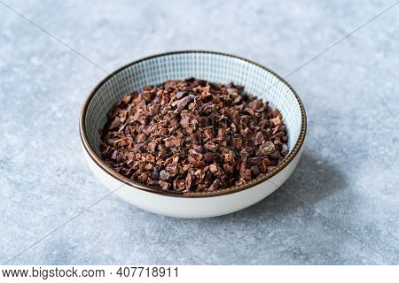 Chocolate Cacao Nibs Or Cocoa Nibs In Bowl Ready To Use On Dark Wooden Surface.