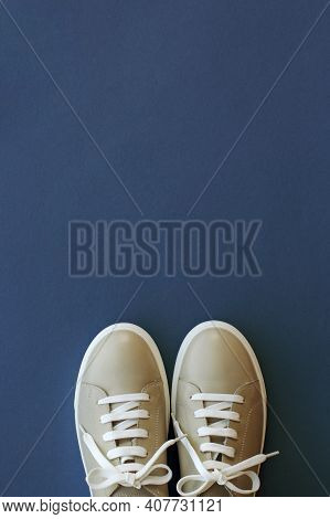 The Toecap Of Beige Leather Sneakers With White Laces On A Blue Background, Top View