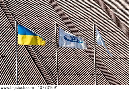 Three Waving Flags - Ukrainian State Flag And Two Tis Logo Flags Against Ribbed Roof Background. Con