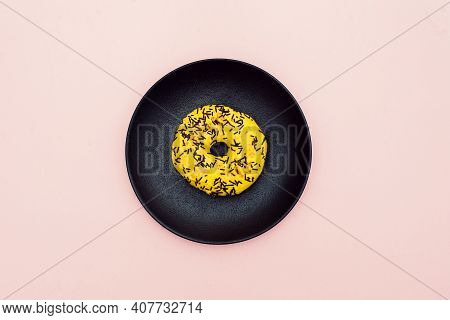 Yellow Donut Decorated With Chocolate Sprinkles Isolated On Pink Background. Top View.