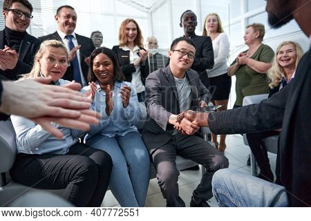 Two business people shaking hands while sitting in meeting room