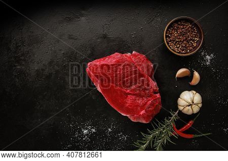 Raw Beef Steak With Spices On A Dark Slate, Stone Or Concrete Background. Top View With Copy Space.