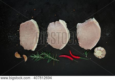 Slices Of Raw Organic Pork Meat With Ingredient For Making On A Dark Metal Background. Top View With