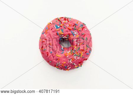Pink Donut Decorated With Colorful Sprinkles Isolated On White Background. Flat Lay. Top View