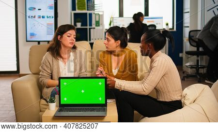 Diverse Businesswomen Analysing Annual Financial Reports Sitting On Couch In Back Of Laptop With Gre