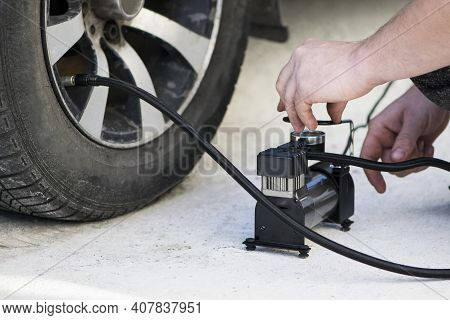 Car Compressor Wheel Pump. A Person Checks The Air Pressure And Fills The Tires Of His Car With Air.