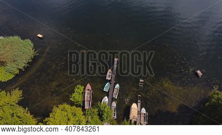 Drone Fly Over Waving River Of Blue Color Surrounded By Local Village With Various Buildings And Wet