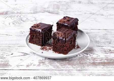 Chocolate Cake With Zucchini Topped With Ganache And Cut Into Portion Pieces On The White Table