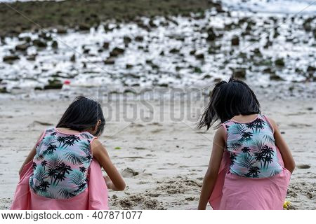 Two Little Kids Making Sand Castle And Playing At Tropical Beach. Little Girls Back View While Playi