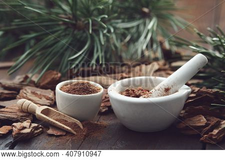 Mortars Of Powdered Pine Bark, Dry Pine Bark On Wooden Board. Branches Of Pine Tree On Background.