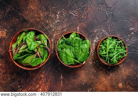 Mix Salad Leafs, Arugula, Spinach And Swiis Chard In Wooden Bowls. Dark Background. Top View
