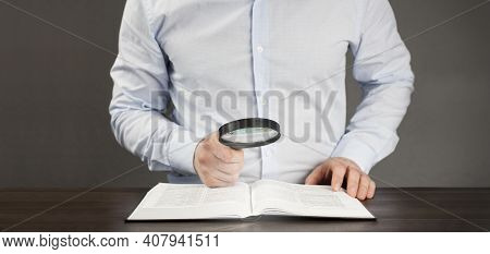 Open Book Bible. Male Businessman Holding A Magnifying Glass In His Hand. Study Research Concept.
