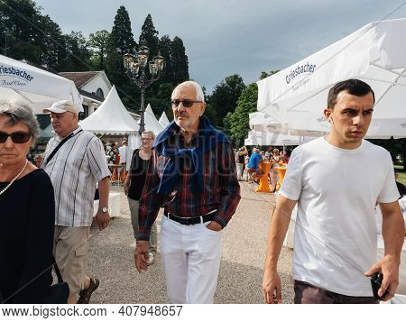 Germany - Circa 2019: Fashionable Senior Man Walking At The Biergarten Restaurant On A Summer Day In