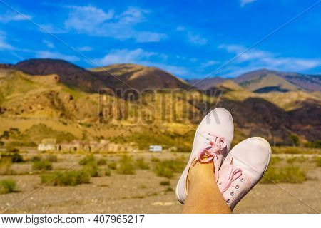 Female Feet In Sierra Alhamilla Landscape, Spain. Caravan At El Chorillo Movie Location In The Backg