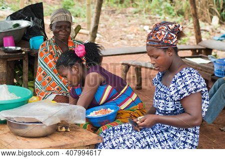 Akoupé, Ivory Coast-august 20, 2015: Three Young Women Sell Food , One Woman Is Very Busy Chopping O
