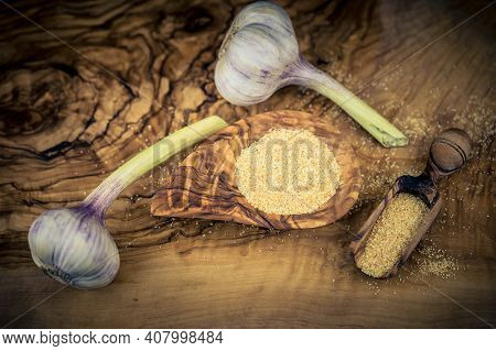 Dried Garlic Granules On Brown Olive Wood