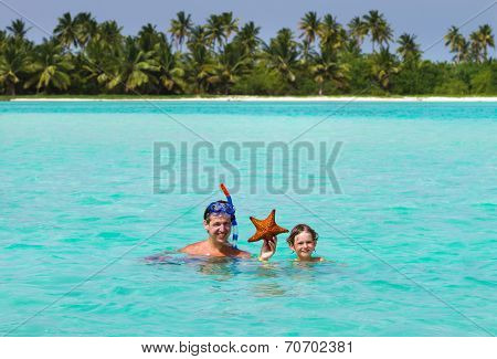 Father And Son Holding A Starfish On A Tropical Beach