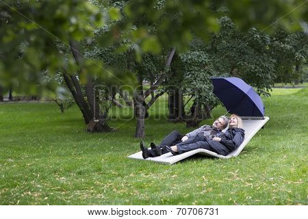 Mature Couple Relaxing On A Deck Chair Under Umbrella