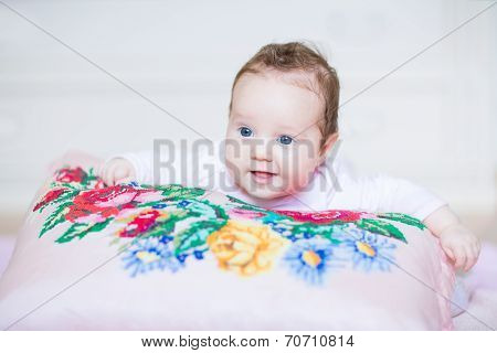 Cute Smiling Baby Girl Relaxing On A Colorful Cross Stitched Pillow