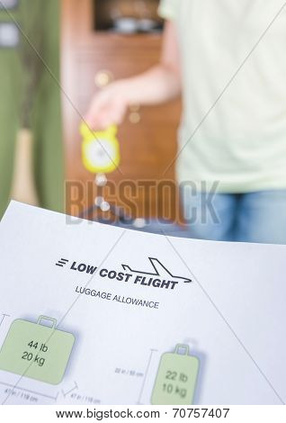 Woman checking luggage weight with a hand balance