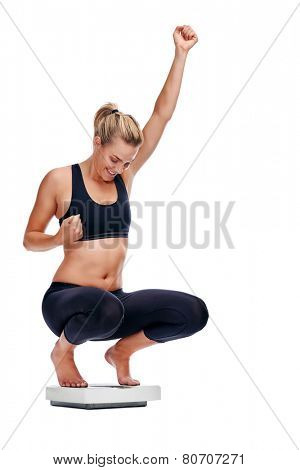 Women on scale cheering for achieving her weight loss goal isolated on white background