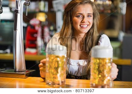 Smiling oktoberfest barmaid with beer at the bar