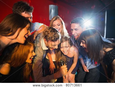Happy friends singing karaoke together in a bar