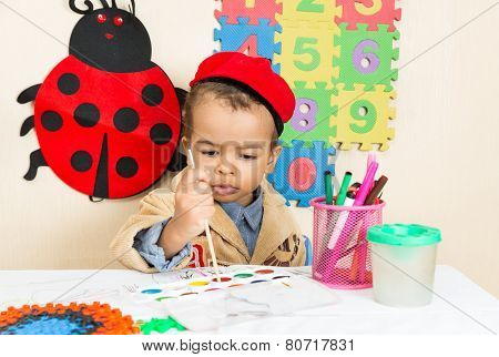 African American Black Boy Drawing With Colorful Pencils In Preschool At Table In Kindergarten