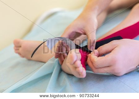 physician puts fixing tape on the child feet
