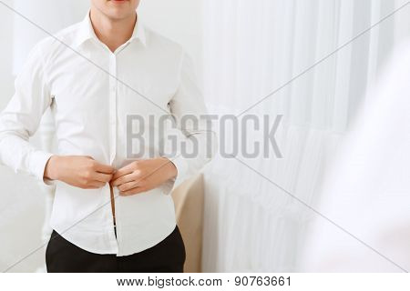 Close up of man buttoning white shirt