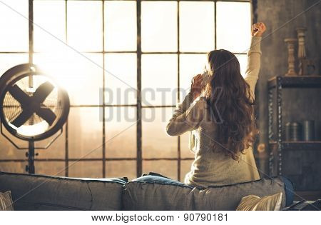 Woman Seen From Behind Talking On Phone In Front Of Loft Window