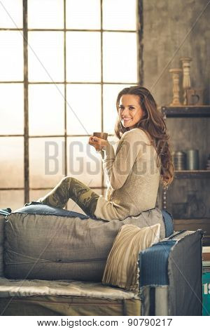 Woman Smiling Looking Over Shoulder Holding Cup In Loft
