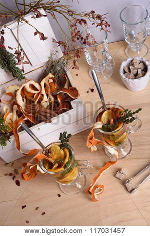 Hot mulled wine with orange slices, cinnamon, thyme on wooden table. Warming drink with ingredients.