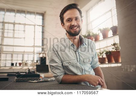 Friendly young designer looking relaxed and confident in his stu