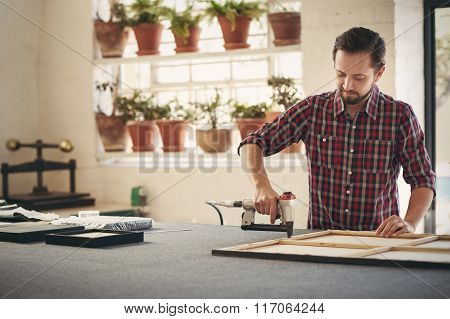 Framer using a work tool to frame an artwork