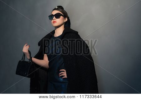 Stylish Wealthy Asian Woman In Retro Forties Fashion With Sunglasses. With Handbag In Her Hand.