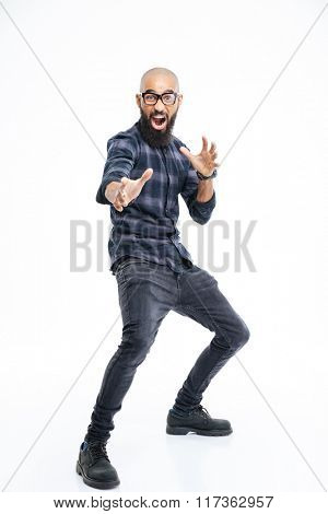Funny baldheaded young african american man with beard standing and showing karate kick 