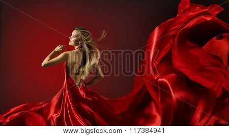 Woman in Red Dress Dancing Fashion Model with Flying Cloth Fabric over red background