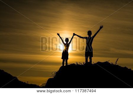 Silhouette success boys on the mountain and sun light behind