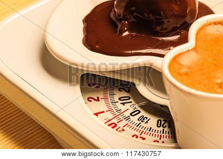 Coffee And Chocolate Cake On Weighing Scale.
