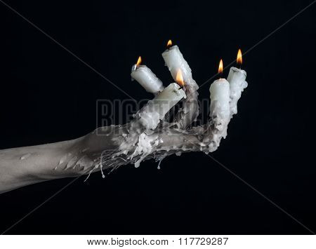 Halloween Theme: On The Hand Wearing A Candle And Dripping Melted Wax On Black Isolated Background