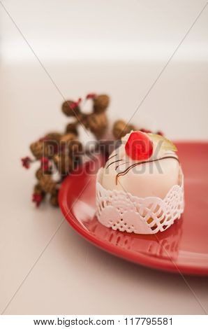 Closeup side view of Italian cassata on a red plate with pine cones