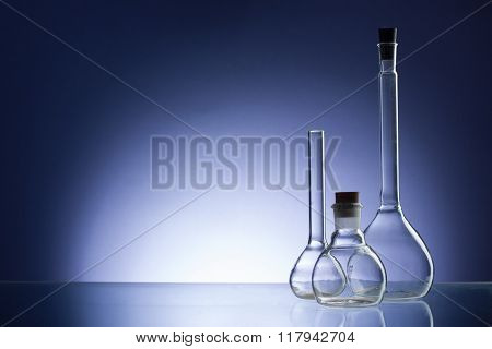 Assorted empty laboratory glassware, test-tubes. Blue tone medical background. Copy space for text.
