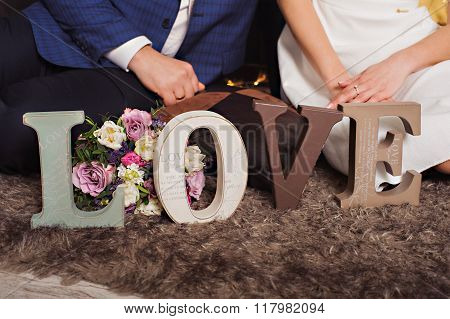 Vintage wooden inscription Love and hands of just married couple.