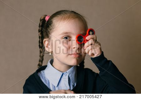 Little caucasian school girl with Fidget Spinner held up to his eyes