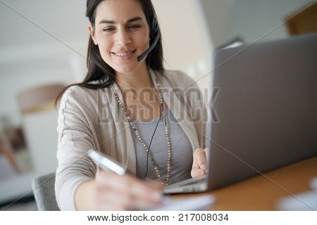Home-office teleoperator talking on phone with headset