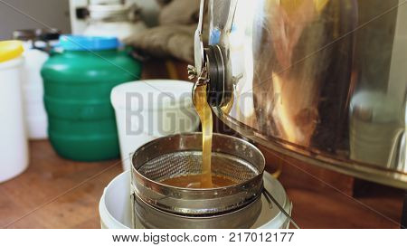 Close-up of honey flowing off harvesting beekeper equipment in apiary