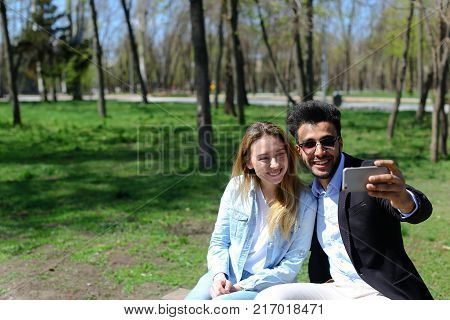 Young couple doing selfie on phone, smiling a lot, doing duck faces and showing peace finger sign. Wife has beautiful long hair and dressed in jeans and white T-shirt. Husband has beard, short hair and dimples. Concept of fast delivery of orders shopping 