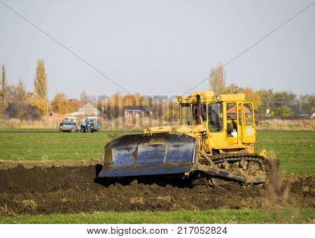 The Yellow Tractor With Attached Grederom Makes Ground Leveling.