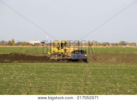 The Yellow Tractor With Attached Grederom Makes Ground Leveling.